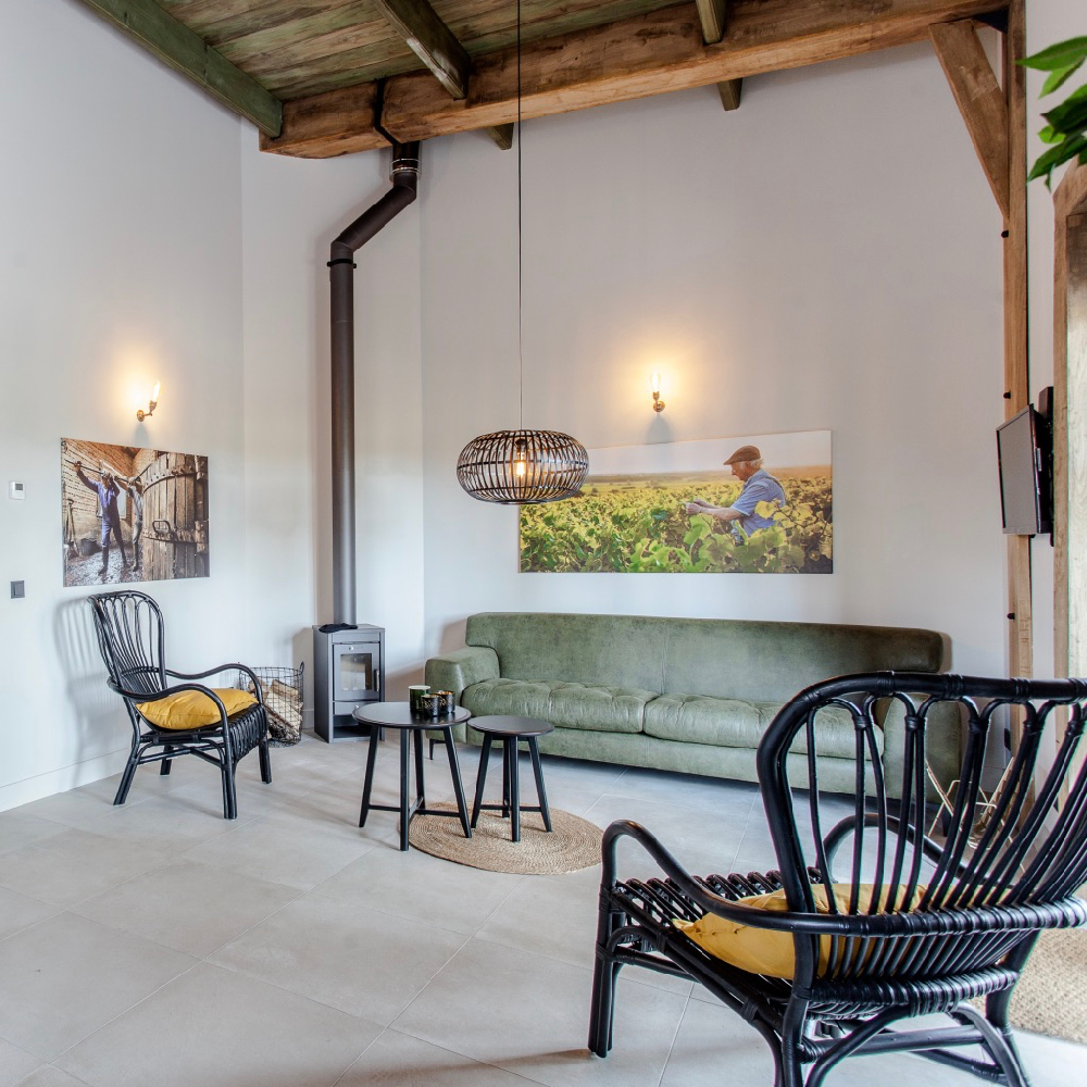 Sitzecke mit schwarzen Rattanstühlen und grünem Sofa in einer Weinloge