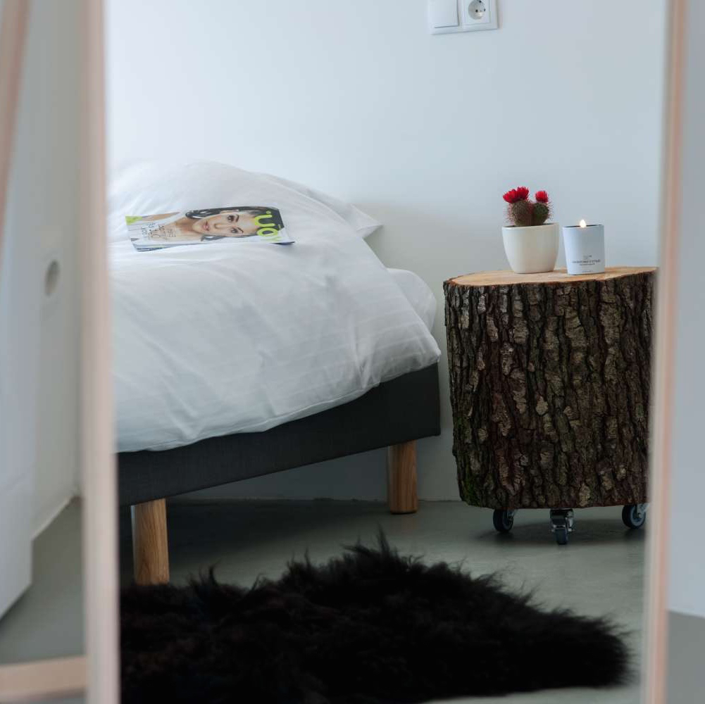 Bett mit Holzkoloss daneben als Nachttisch