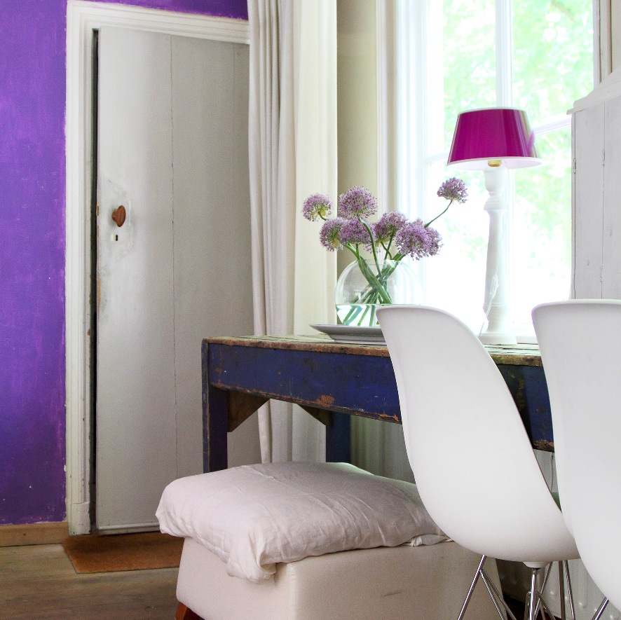 Blauer Holztisch mit Blumenvase und weißen Stühlen im B&B-Zimmer