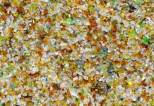 Microplastiche: l’invisibile che ci abita (e la speranza che nasce dall’ingegno) Vista dall'alto di un accumulo di minuscoli frammenti colorati di plastica e vetro frantumato.