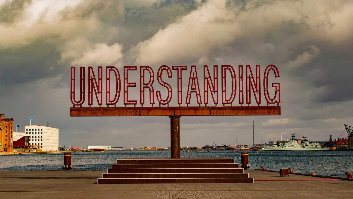 Large UNDERSTANDING sign over waterfront with cloudy sky
