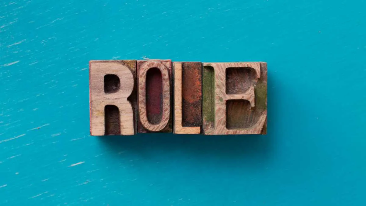 Wooden blocks spelling ROLE on a teal background