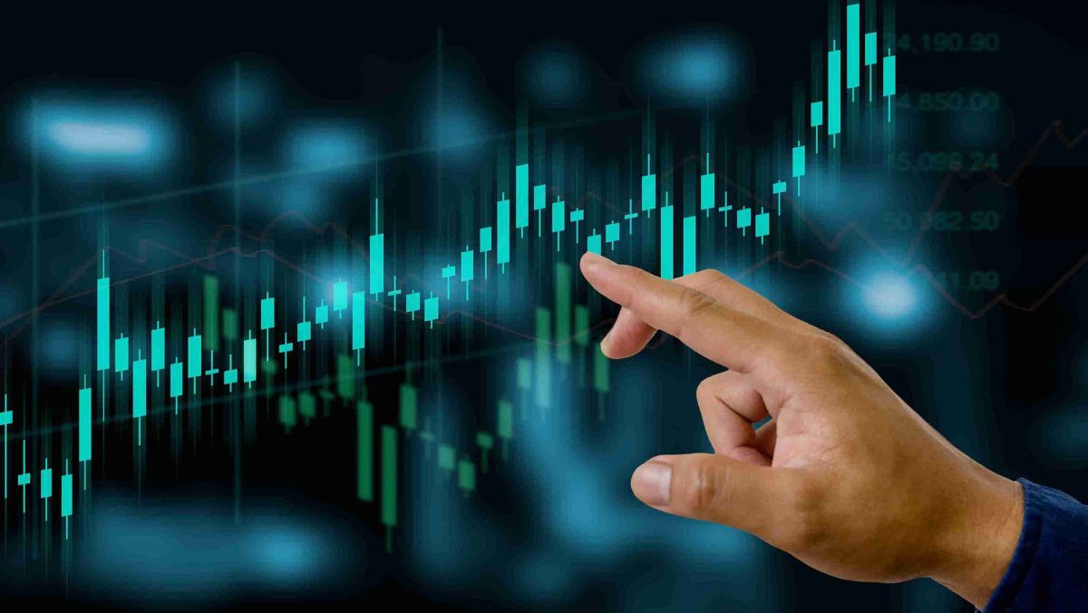 A hand points towards the radiant teal-coloured candlestick patterns