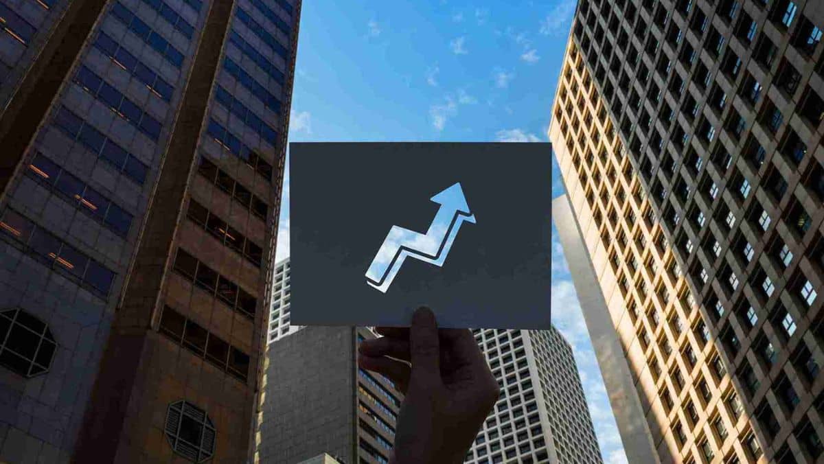 A piece of paper displaying a central cutout shaped like an upward arrow set against a skyline of buildings