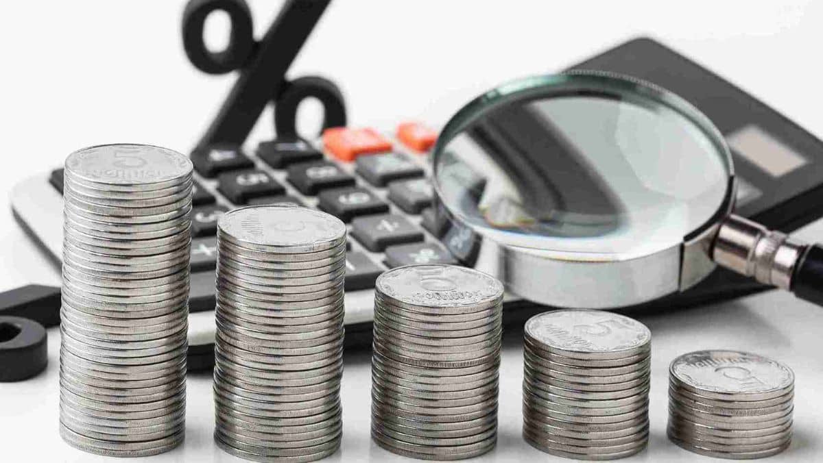 Arranged stack of coins with a calculator magnifying glass and a percentage icon behind
