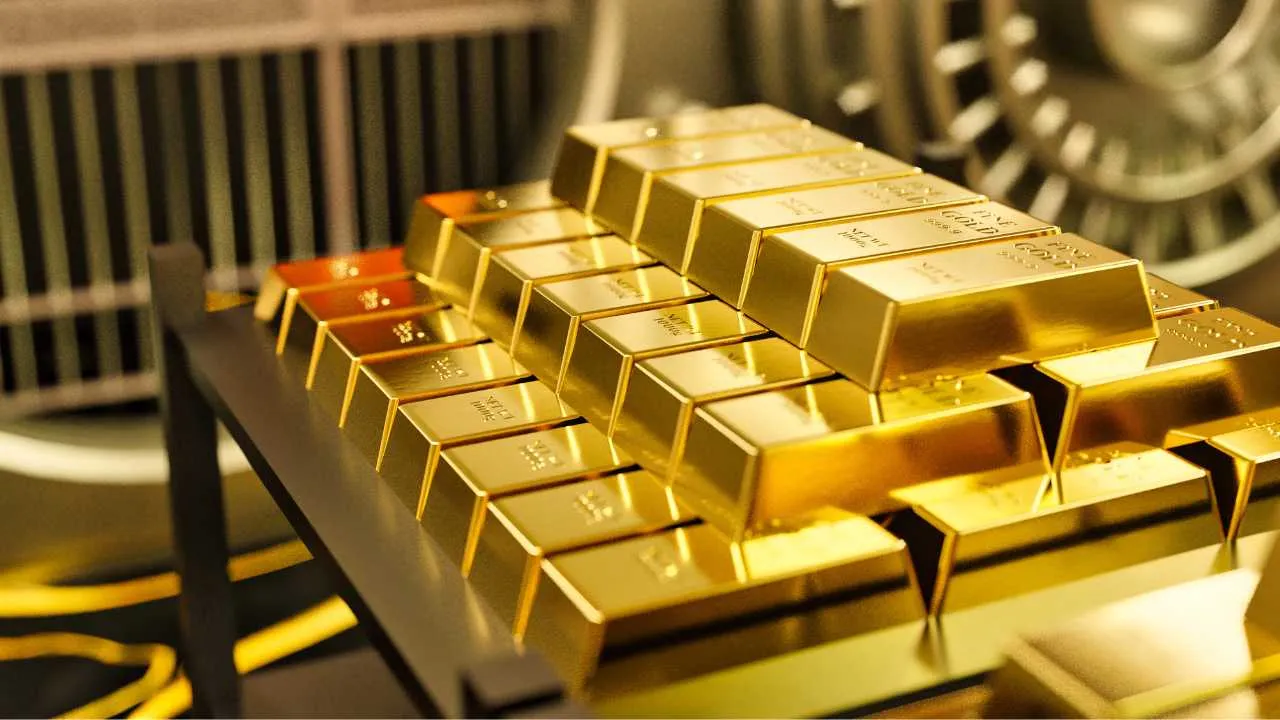 Gold bars on a conveyor belt with a vault in the background