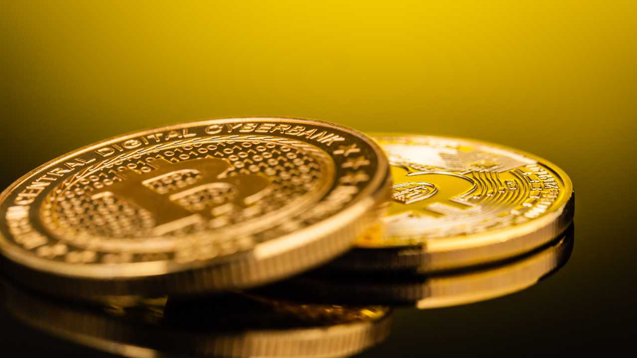 Gold coloured crypto coins on a reflective surface
