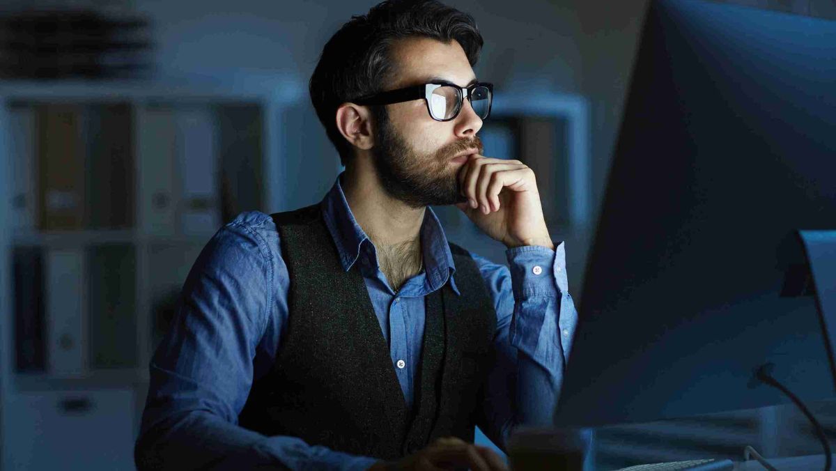 Man working in an office at night looking at a computer screen