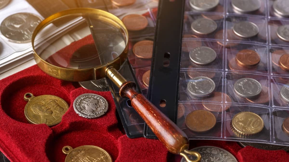 Numismatics. Old collectible coins made of silver on a wooden table.Coins in the album.Collection of old coins. Magnifying glass.