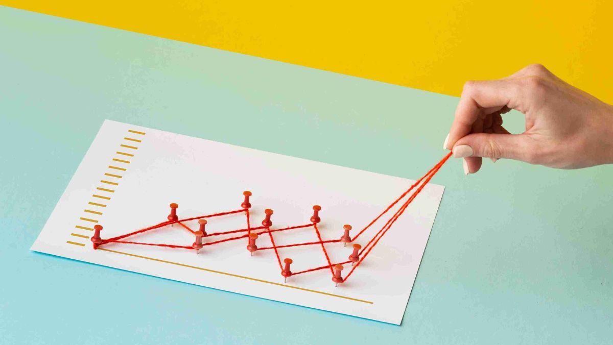 Red pins are positioned to create angles, connected by yarn that is stretched upward by someone