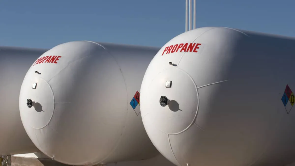White propane storage tank against a blue sky with clouds