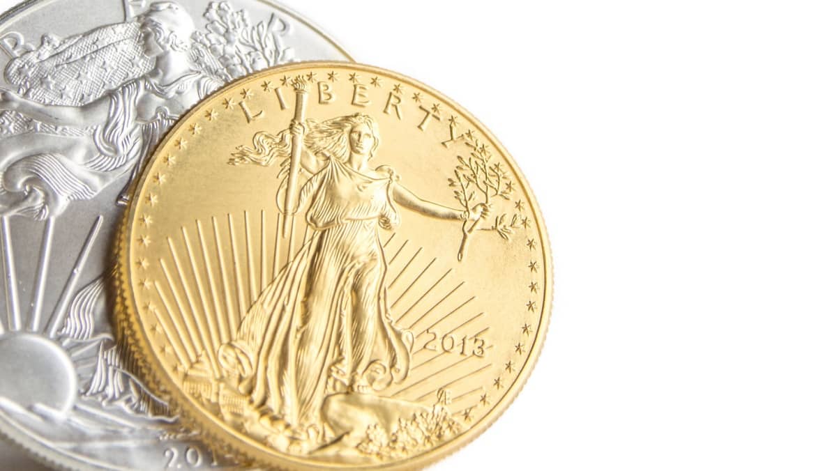 closeup of silver eagle and golden american eagle one ounce coins on white background placed on left side