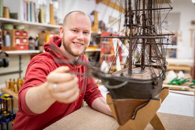 A conservation student working on a model clipper boat in the furniture conservation workshop