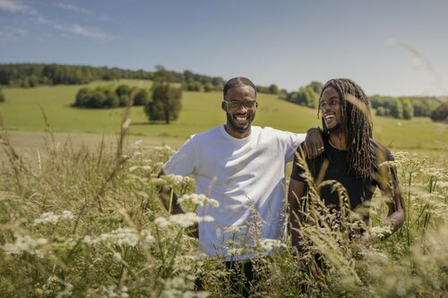 Resolve Collective artists Seth and Akil stand waist height in cow parsley with the parkland behind them