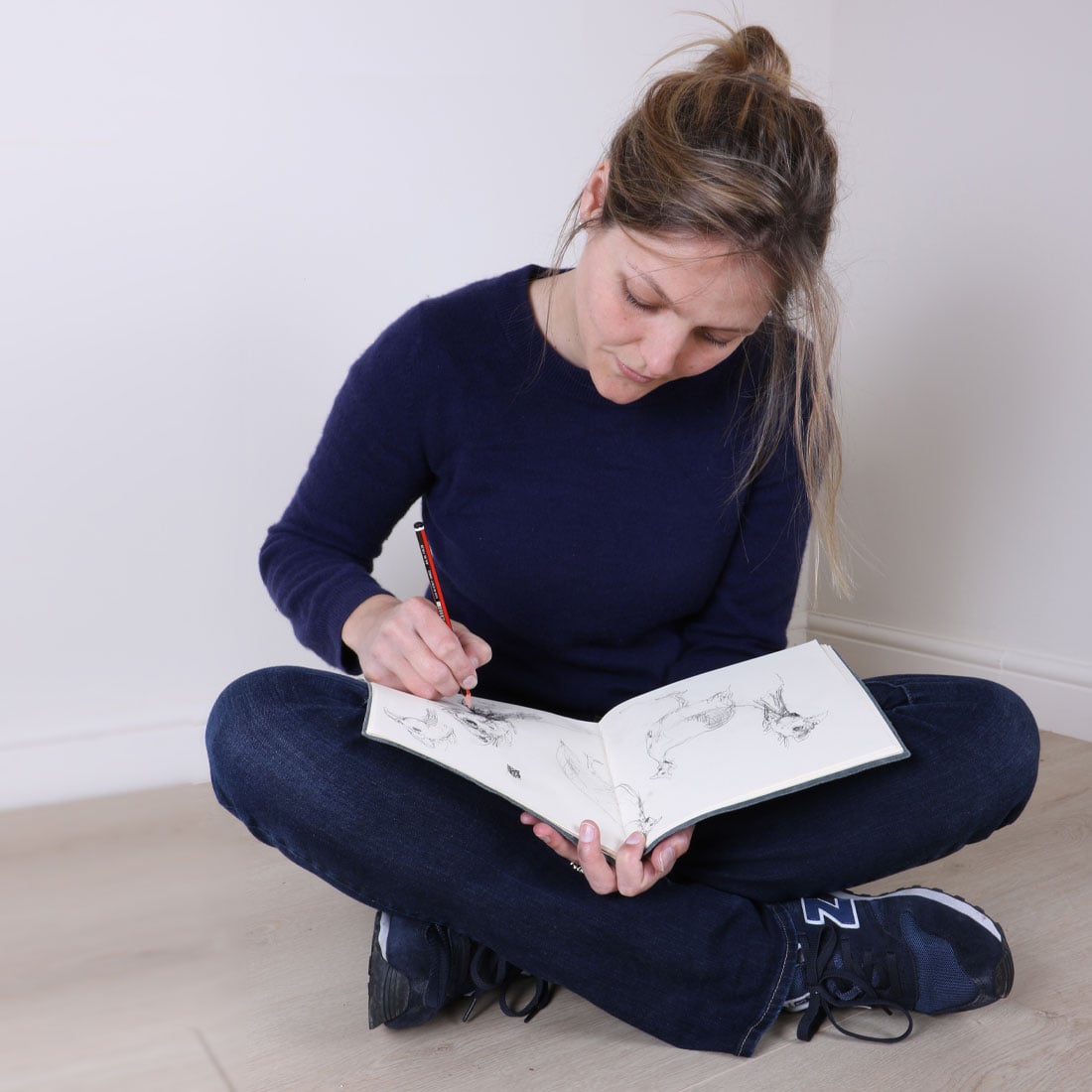Zaza Shelley sitting on the studio floor with a sketchbook